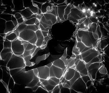 grey scale photography of woman swum in swimming pool thumbnail