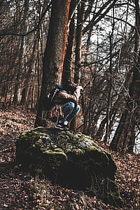 person sitting on green stone holding DSLR camera thumbnail