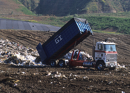 white and blue dump truck dumping garbage during daytime thumbnail