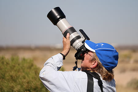 man using white and black DSLR camera thumbnail