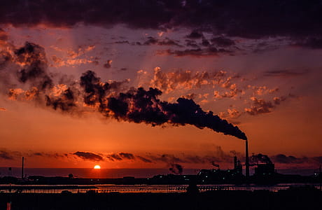 Industrial factory smoke from smokestacks over sunset sky thumbnail
