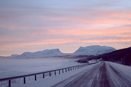snow-covered road near ocean and mountains thumbnail