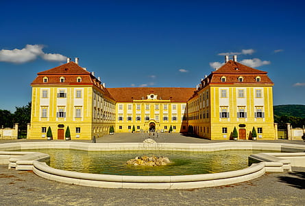 yellow and red building with fountain during daytime thumbnail