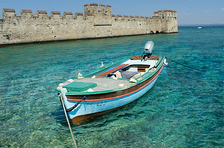 blue and brown outboard boat near brown concrete castle thumbnail