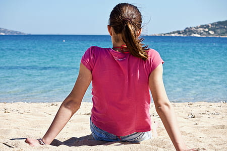 woman sitting on sand near sea at daytime thumbnail