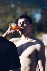 selective focus photography of man drinking labeled bottle thumbnail