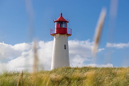 white and red lighthouse on hill during daytime thumbnail