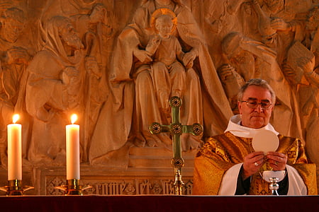 priest standing beside candles thumbnail