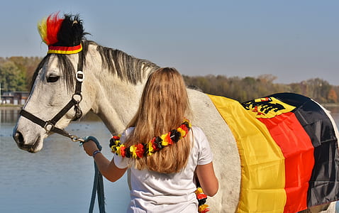 woman in white t-shirt beside white horse near body of water thumbnail