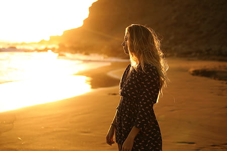 woman standing on shoreline during golden hour thumbnail