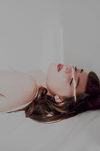 woman in white sleeveless top laying on bed thumbnail
