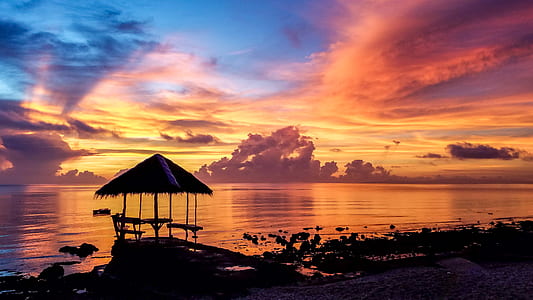 nipa hut near body of water during sunset thumbnail
