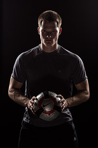man wearing gray crew-neck t-shirt and holding gray and black Nike soccer ball thumbnail