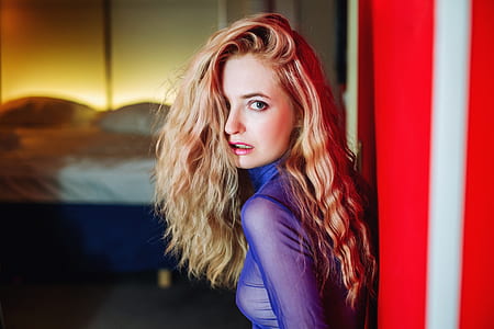 woman leaning on red wall inside room shallow focus photography thumbnail