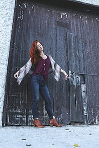 Woman in Red Tank Top With Brown Scarf Standing Near Black Wooden Door Closed thumbnail