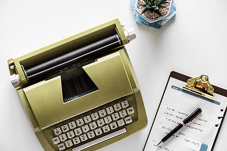 brown typewriter beside clipboard on white surface thumbnail