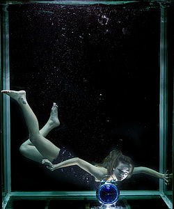 woman in black glittered dress diving in tank full of water with desk alarm clock thumbnail