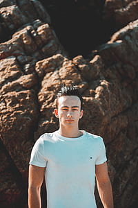 man standing beside boulder thumbnail