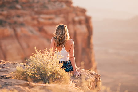 woman sitting on cliff near grass at daytime thumbnail