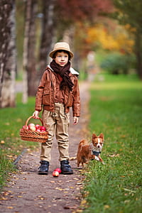 boy in brown leather jacket standing beside dog on pathway thumbnail