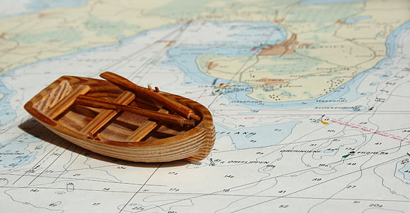 brown wooden miniature boat on top of map thumbnail