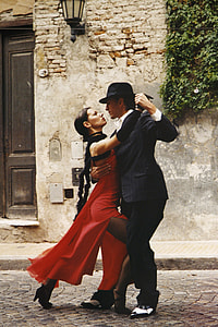 man in black suit and woman in red slit dress dancing beside grey concrete wall thumbnail