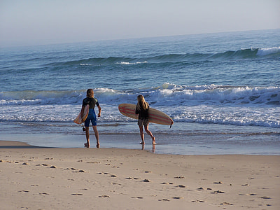two person holding surfboard walking beside seashore thumbnail