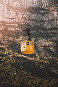 yellow cable car near rocky cliff during daytime thumbnail
