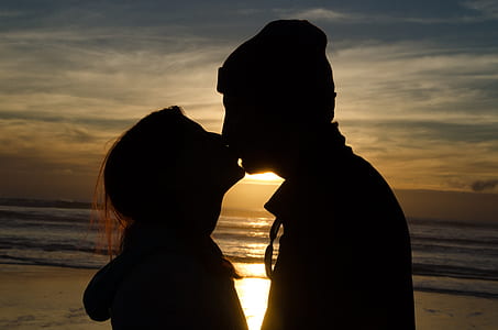silhouette of man and woman kissing near beach thumbnail