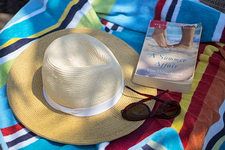 beige sunhat beside sunglasses and book thumbnail