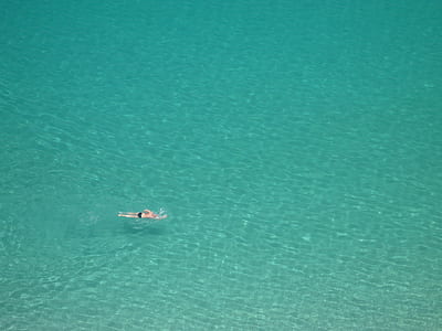 person swimming on body of water thumbnail