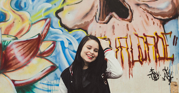 woman, varsity jacket, standing, wall, graffiti, piercing thumbnail