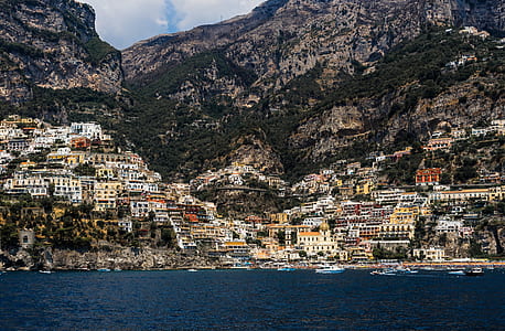 buildings near body of water and mountains thumbnail