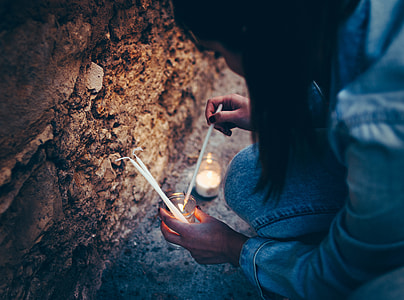 woman lighting candles near rocks thumbnail