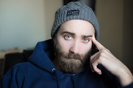 man wearing beanie cap and pullover hoodie near white painted wall thumbnail