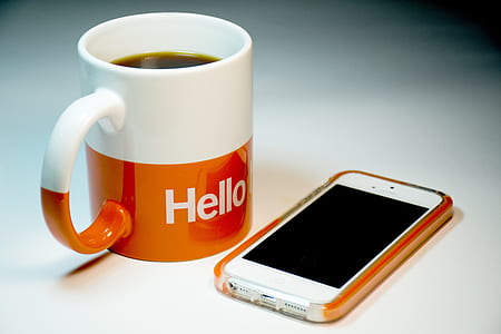 white iPhone 5 with orange case near white and orange hello ceramic coffee mug thumbnail