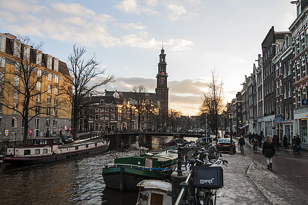 people walking near body of water with boats in middle of town during daytime thumbnail