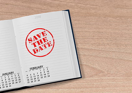 notebook with save the date stamp on top of brown wood surface thumbnail