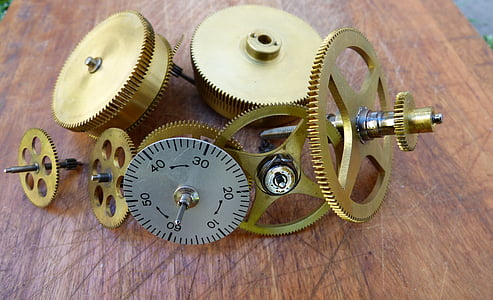 round brass-colored gears and gray analog dial on brown surface thumbnail