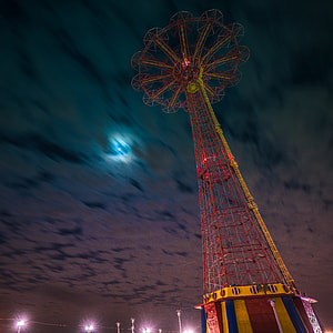 red and yellow amusement park ride under cloudy night sky thumbnail
