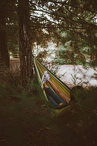 person wearing blue jeans on green and yellow hammock thumbnail