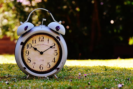 analog alarm clock reading 10:10 time on grass field thumbnail
