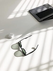 black framed sunglasses on top of white surface near AirPod case thumbnail
