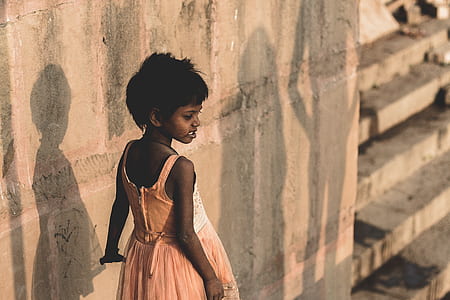 girl in pink dress walking beside concrete wall thumbnail