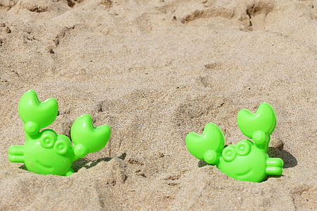 two green crab plastic toys on brown sand thumbnail