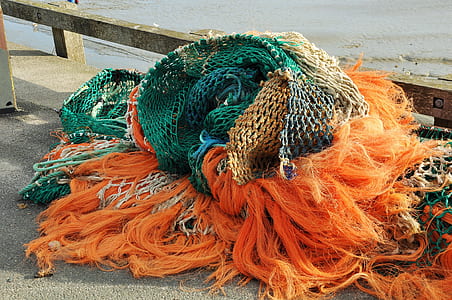 orange fishing net near brown fence thumbnail