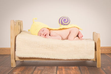 baby wearing yellow hat lying on sofa thumbnail