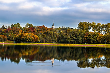 green trees near body of water under white clouds thumbnail