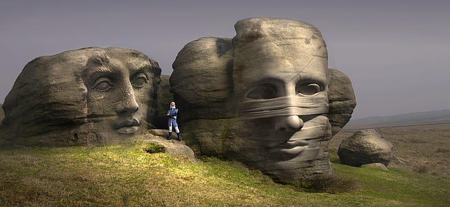 person's faces rock formation near green grass field thumbnail