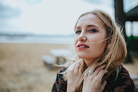 Beautiful blonde woman relaxing with a can of coke on a tree stump by the beach thumbnail